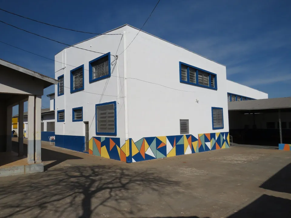 Pátio interno depois da reforma, com parede pintada de branco e faixa geométrica colorida